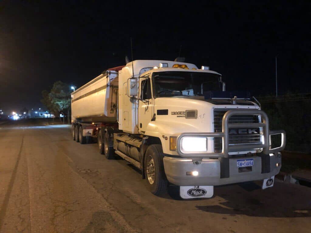 A large Mack truck parked on the side of a road at night in Perth